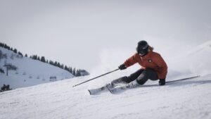 person skiing down a slope with mountain and chairlift in the background