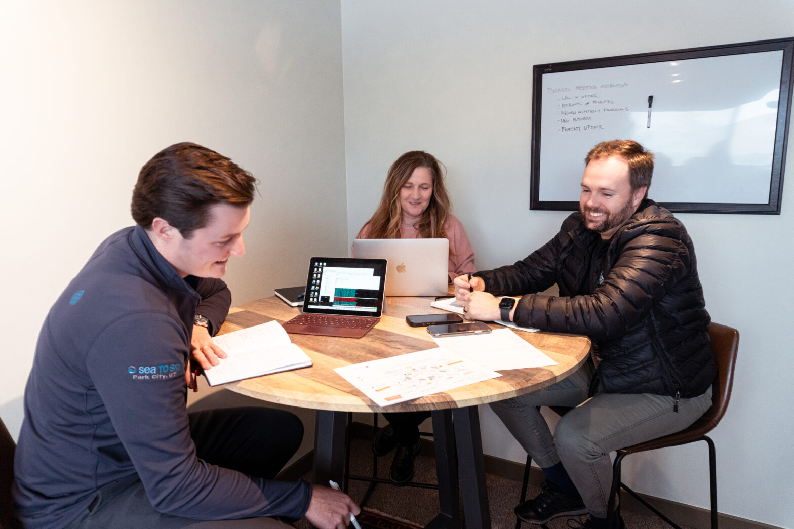 2 men and a woman in a HOA management meeting around a round table.