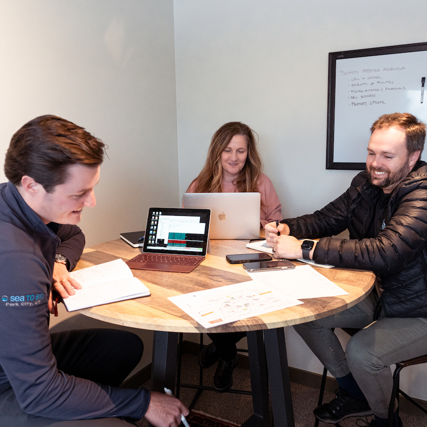 2 men and a woman in a HOA management meeting around a round table.
