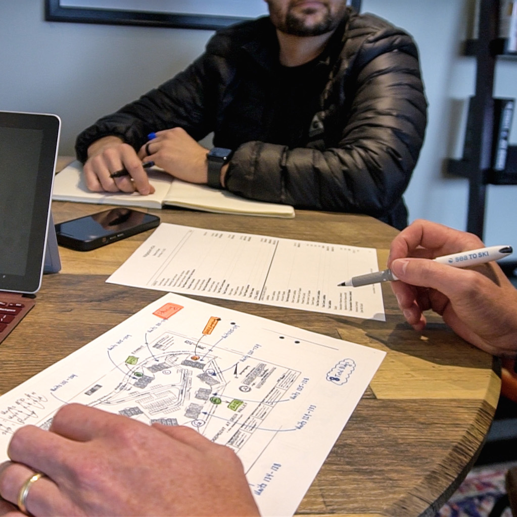 Maps, computer, cellphone and hands on of people on the table in a meeting