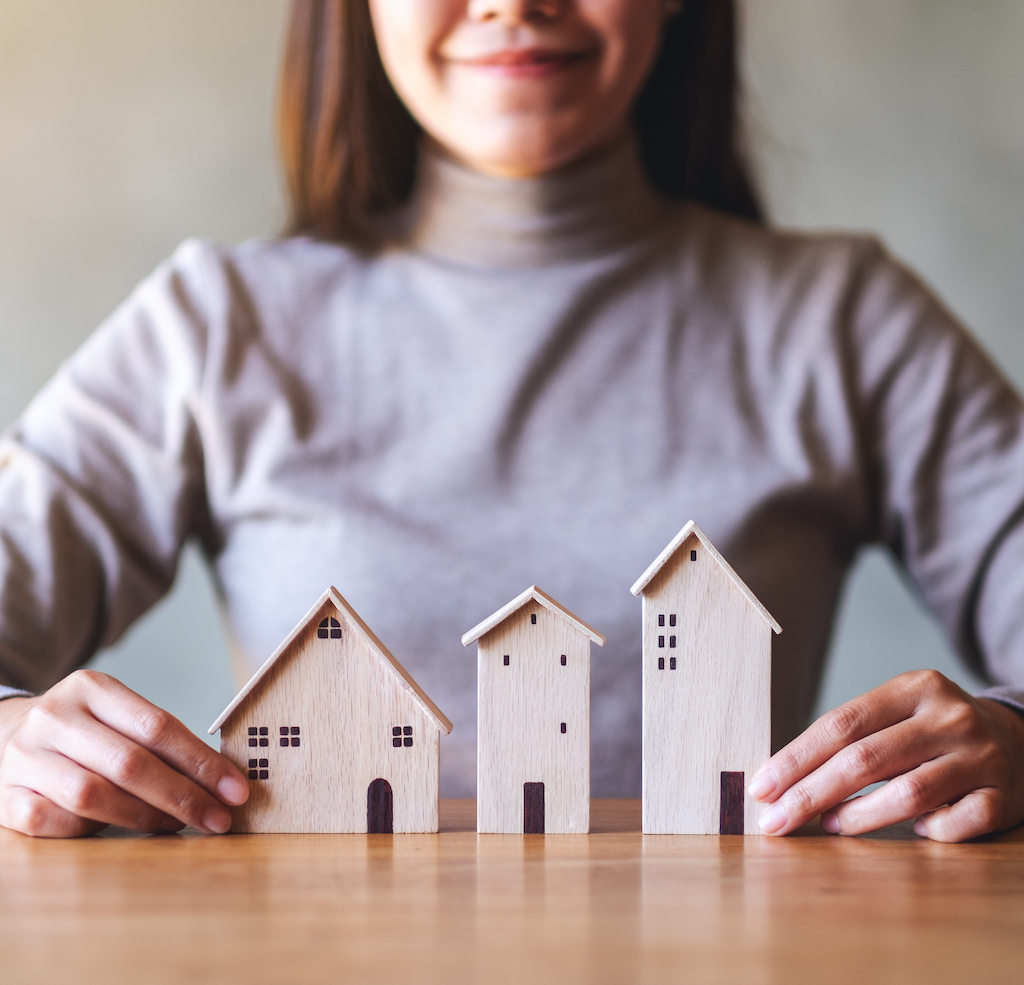 Closeup image of a woman holding wooden house models on the table